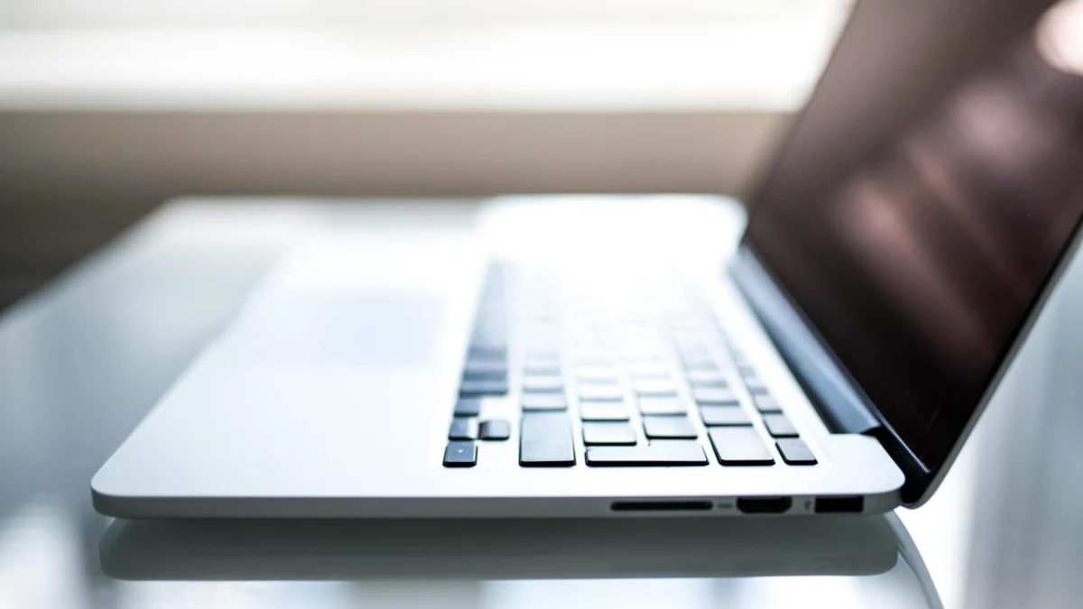 Free Elegant side view of a laptop on a glossy table with natural lighting indoors. Stock Photo