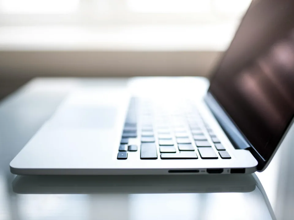Free Elegant side view of a laptop on a glossy table with natural lighting indoors. Stock Photo