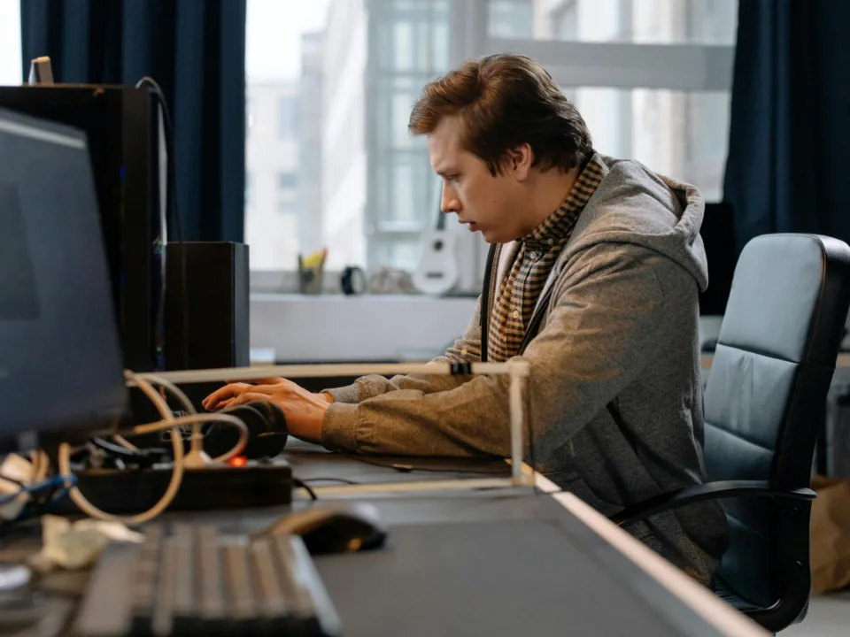 Free A concentrated professional working at a computer in a modern office setting. Stock Photo