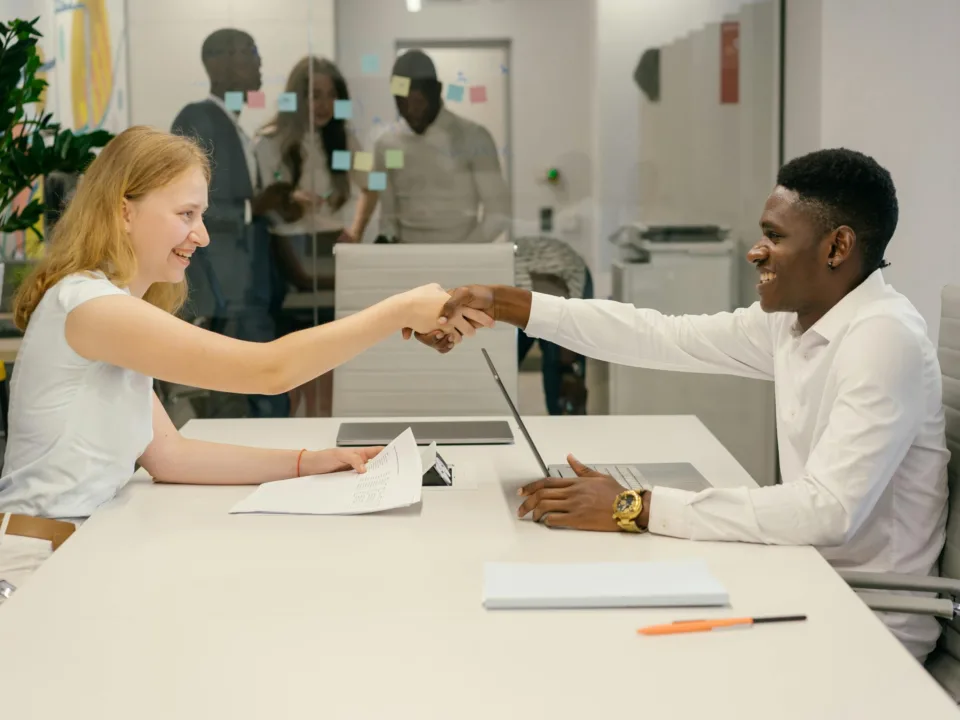 Free Business professionals completing a successful deal with a handshake in a modern office setting. Stock Photo